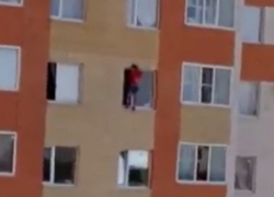 На грани смерти находится неизвестный молодой человек, свисающий из окна дома в Ставрополе